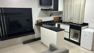 a kitchen with a sink and a large television at Casa há 9 min Aeroporto GRU in Guarulhos