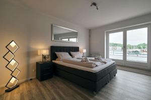 Schlafzimmer mit einem Bett mit einem Spiegel und einem Fenster in der Unterkunft Schiffbrücke in Flensburg