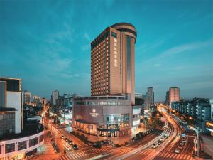 um edifício alto numa cidade com trânsito numa rua em Wanda Yi Hotel Wuxi em Wuxi