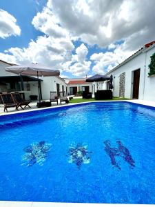 a large blue swimming pool in front of a house at Alojamiento El Miajon de los Castúos in Valdesalor