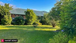 a large yard with a house in the background at Bermagui Breeze Holiday House 5 bedroom 18-20 Mumbulla Street - Bermagui in Bermagui
