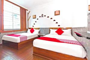 a bedroom with two beds with red pillows at OYO 210 Hotel Five 2 in Kota Kinabalu
