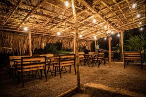 a group of wooden tables and chairs under a pavilion at TENT LIFE in Vagamon