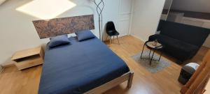 Un dormitorio con una gran cama azul y un sofá en F2 duplex standing de 35 m2 à 3 min du canal de l'ourcq en Tremblay En France