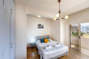 a white bedroom with a bed and a window at Mackenzie Beachfront Eftyhia Suite in Larnaca