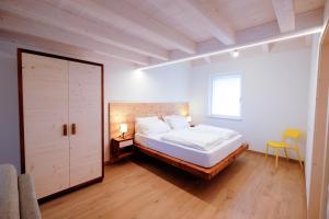 a bedroom with a white bed and a yellow chair at Casa Carolina in Levico Terme