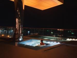 a woman sitting in a hot tub at night at Edge Central PATTAYA Sky Residence with Infinity Pool & Free Netflix in Pattaya Central