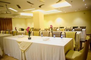 The Secure Inn Hotel Muscat في مسقط: قاعة اجتماعات مع طاولات وكراسي عليها زهور