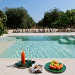 a plate of fruit and a drink next to a swimming pool at Masseria Pezze Galere-La Casa del Fico con piscina idromassaggio privata in Fasano