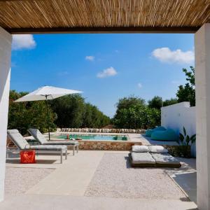 a swimming pool with chairs and an umbrella and a swimming pool at Masseria Pezze Galere-La Casa del Fico con piscina idromassaggio privata in Fasano