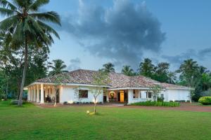 a white house with a palm tree in a yard at Ceylo Villas in Bentota +44 photos