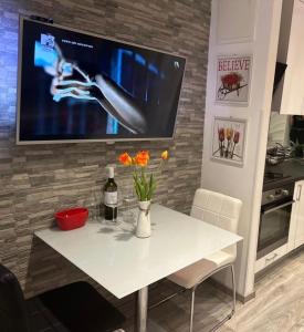 a white table with flowers and a tv on a wall at Mitella studio apartman in Solin