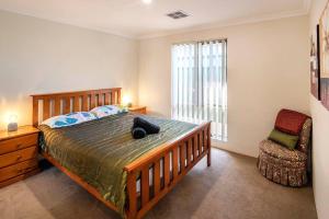 Un dormitorio con una cama y una silla y una ventana. en Duke Cottage - pet friendly near beach., en Busselton