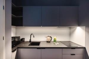 a kitchen with black cabinets and a sink at By Monte Apartment - Destigo Hotels in Sopot