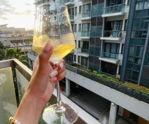 a person holding up a glass of wine on a balcony at Lovely Unit with free wi-fi & netflix I across Naia T3 airport in Manila