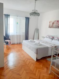 a bedroom with a white bed and a wooden floor at Apartments Sara in Podstrana
