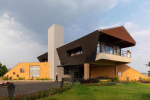 a modern house with a black roof at Pearl Lakeview Mansion by StayVista - Lakeside villa with Infinity pool, Jacuzzi, In-house theatre & Games room in Igatpuri