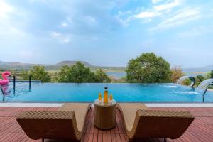 a swimming pool with a table with drinks on it at Pearl Lakeview Mansion by StayVista - Lakeside villa with Infinity pool, Jacuzzi, In-house theatre & Games room in Igatpuri