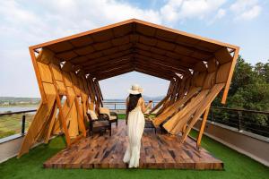 a woman in a white dress and hat in a gazebo at Pearl Lakeview Mansion by StayVista - Lakeside villa with Infinity pool, Jacuzzi, In-house theatre & Games room in Igatpuri