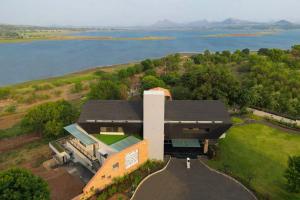 an aerial view of a building with a lake at Pearl Lakeview Mansion by StayVista - Lakeside villa with Infinity pool, Jacuzzi, In-house theatre & Games room in Igatpuri +45 photos