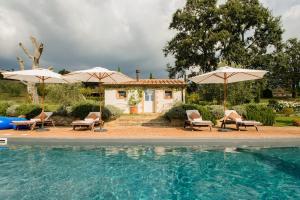 een zwembad met parasols en stoelen en een huis bij Villa Countryside Maremma in Scansano
