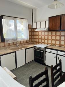 cocina con armarios blancos y estufa negra en Villa Lula, en Nea Styra