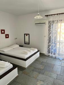 a white bedroom with two beds and a window at Villa Lula in Nea Stira
