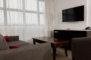 - un salon avec une télévision, un canapé et une table dans l'établissement Capricorn Hotel Suva, à Suva