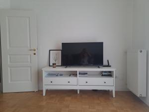 ein weißes Entertainment-Center mit einem Flachbild-TV darauf in der Unterkunft Elina Apartment in Meran