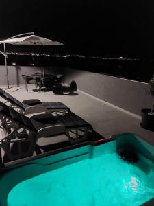 a swimming pool with chairs and a table and an umbrella at Penthouse Petra with hot tub in Kali
