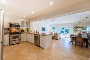 a kitchen with white cabinets and a dining room with a table at Pineapple Palms Resort Style Pool Villa! Sleeps 12 in West Palm Beach