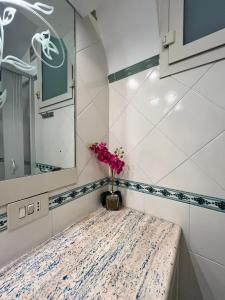 La salle de bains est pourvue d'un lavabo et d'un vase fleuri. dans l'établissement Casa Tutti Frutti, à Positano