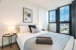 a bedroom with a large white bed with windows at Your Gateway to Sports and Entertainment-00215 in Melbourne