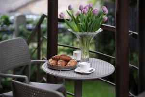 una mesa con un jarrón de tulipanes y un tazón de cruasanes en Villa ACACIA, en Kaunas