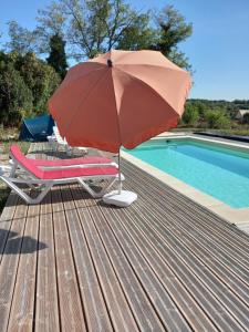 un parasol rouge assis sur une terrasse à côté d'une piscine dans l'établissement LE PARDÈS BnB, à Rocamadour