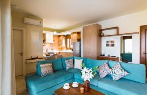un salon avec un canapé bleu et une cuisine dans l'établissement Muses Beach Villas - Cleo, à Siteía