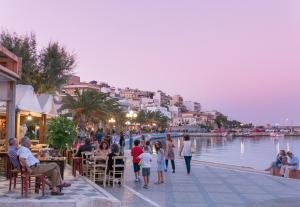 a group of people sitting at tables near a body of water at Muses Beach Villas - Erato in Sitia