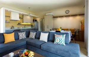 un soggiorno con divano blu e una cucina di Muses Beach Villas - Thalia a Sitia