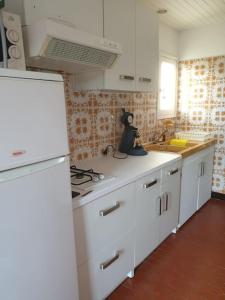 a kitchen with white cabinets and a stove top oven at Appartement, prive terrasse, parking et jardin in Le Boulou