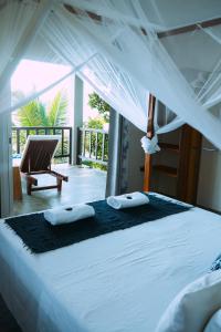 ein Schlafzimmer mit einem Himmelbett und einem Stuhl in der Unterkunft Komba on the Rocks in Nosy Komba