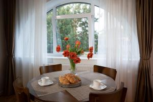 uma mesa com um vaso de flores e uma janela em Villa ACACIA em Kaunas