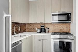 a white kitchen with a sink and a microwave at Tribeca Studio w Pool Roofdeck Gym View NYC-273 in New York