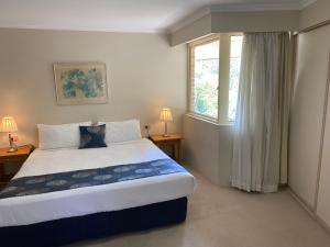 Wahroonga Furnished Apartments في هورنسبي: غرفة نوم بسرير كبير ونافذة