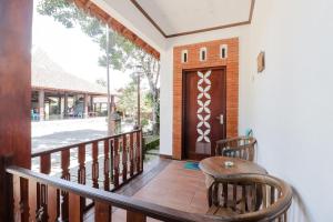 uma varanda com uma porta de madeira e uma mesa e cadeiras em Hotel Ndalem Ayem Syariah em Magelang