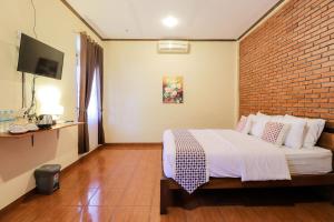 um quarto com uma cama e uma parede de tijolos em Hotel Ndalem Ayem Syariah em Magelang