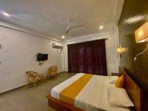 a bedroom with a bed and two chairs in it at Lina Hotel in Habarana