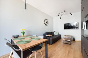 a dining room and living room with a table and chairs at Wola Skwer Happy Apartment in Warsaw