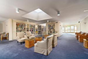 Wahroonga Furnished Apartments في هورنسبي: مكتبة فيها كراسي وطاولات ورفوف كتب