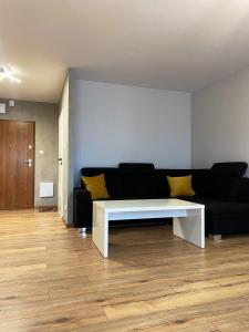 a living room with a black couch and a white table at Apartament Sanok nad stawami in Sanok