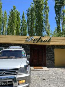a car parked in front of a building with a sign at Rafsal A Countryside Cottage in Skardu